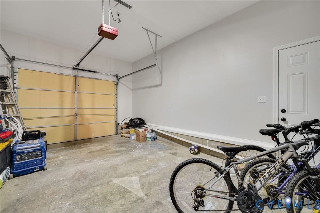 5612 Jessup Station Place, Chesterfield, VA 23234 Spacious garage featuring a light-toned wood-finish garage door, white interior door, light gray painted walls, and concrete flooring