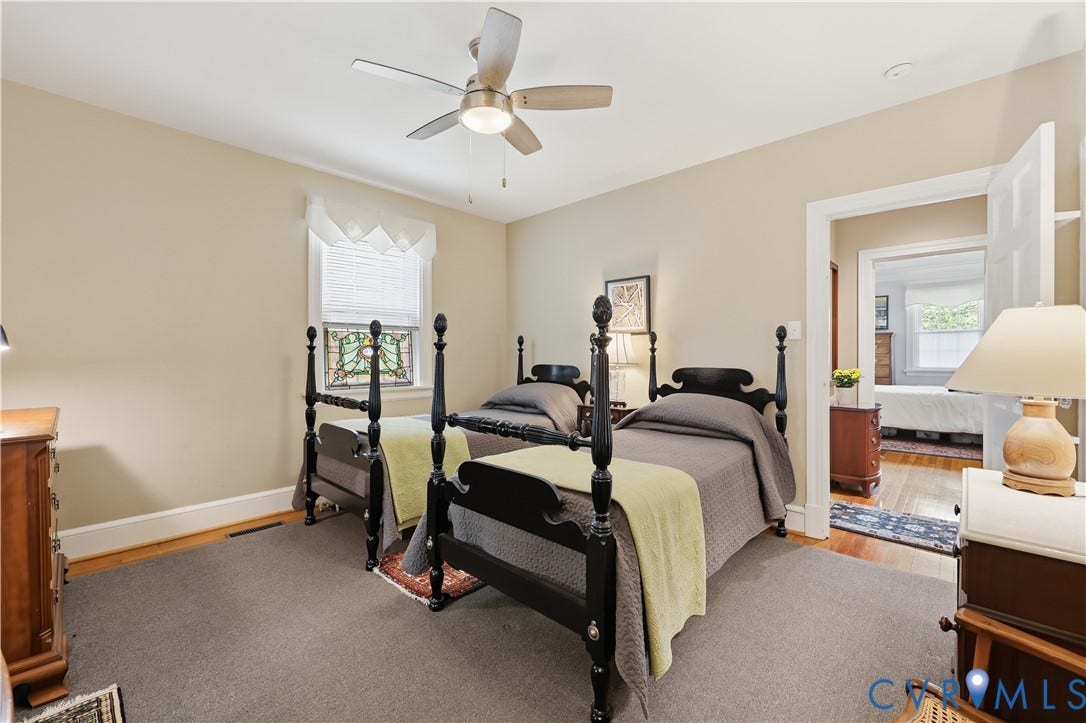 4207 W Grace Street, Sauer's Gardens, Richmond, VA 23230 Carpeted room featuring a ceiling fan with integrated lighting, a window with a stained-glass panel, and a doorway opening to a room with hardwood flooring