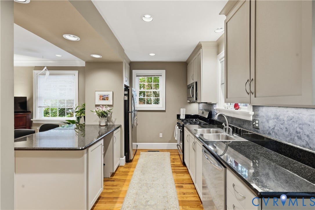 4207 W Grace Street, Sauer's Gardens, Richmond, VA 23230 Galley kitchen featuring dark countertops, light cabinetry, stainless steel appliances, and wood-finish flooring