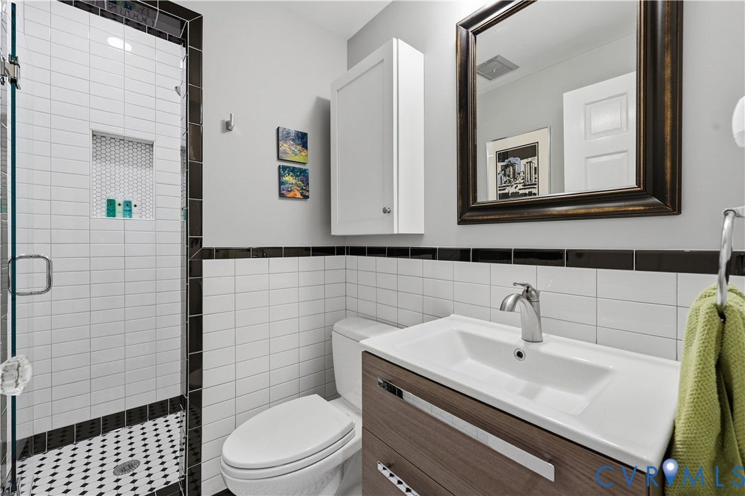 4207 W Grace Street, Sauer's Gardens, Richmond, VA 23230 Contemporary bathroom featuring a glass-enclosed shower with white subway tile, a built-in shower niche, and black and white penny tile flooring