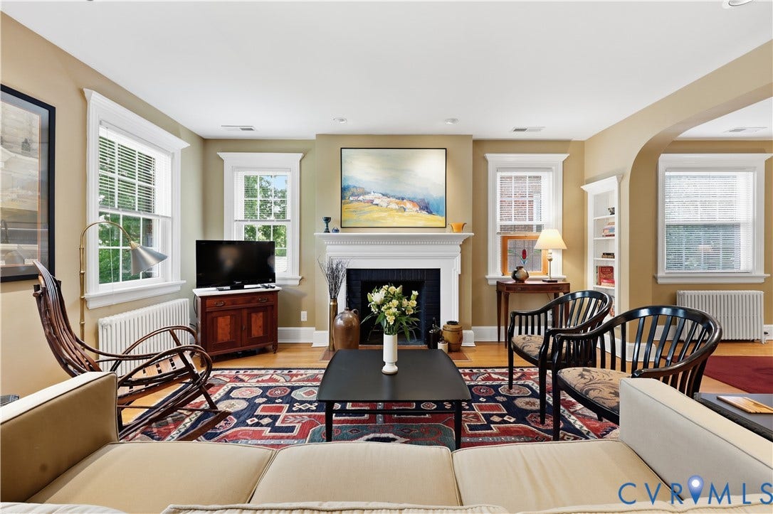 4207 W Grace Street, Sauer's Gardens, Richmond, VA 23230 Spacious living area featuring hardwood flooring, a decorative fireplace with a white mantel, multiple windows with natural light, and an arched entryway