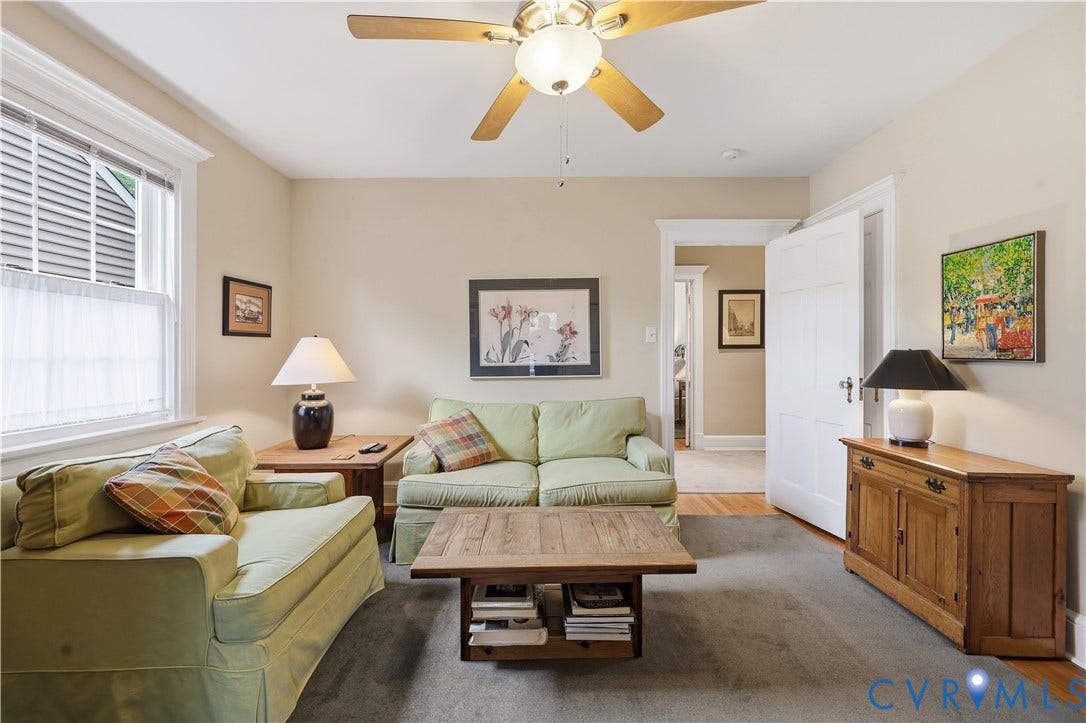 4207 W Grace Street, Sauer's Gardens, Richmond, VA 23230 Carpeted living area featuring a ceiling fan with light fixture, hardwood flooring visible at the room's edge, white trim, and an open doorway
