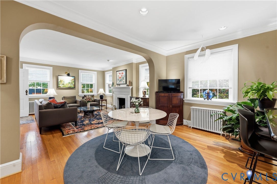 4207 W Grace Street, Sauer's Gardens, Richmond, VA 23230 Open-concept dining and living areas featuring hardwood flooring, arched entryway, crown molding, and a traditional fireplace with mantel
