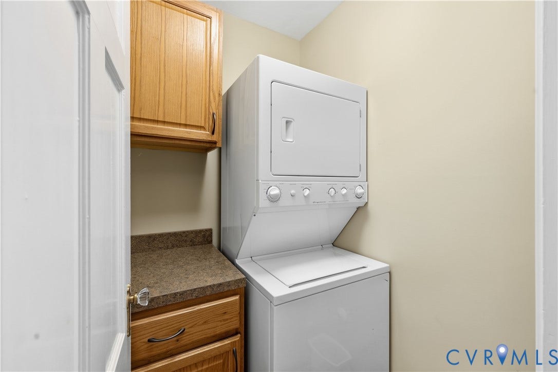 4207 W Grace Street, Sauer's Gardens, Richmond, VA 23230 Dedicated laundry area featuring a stacked washer and dryer unit, wood cabinetry, and a countertop