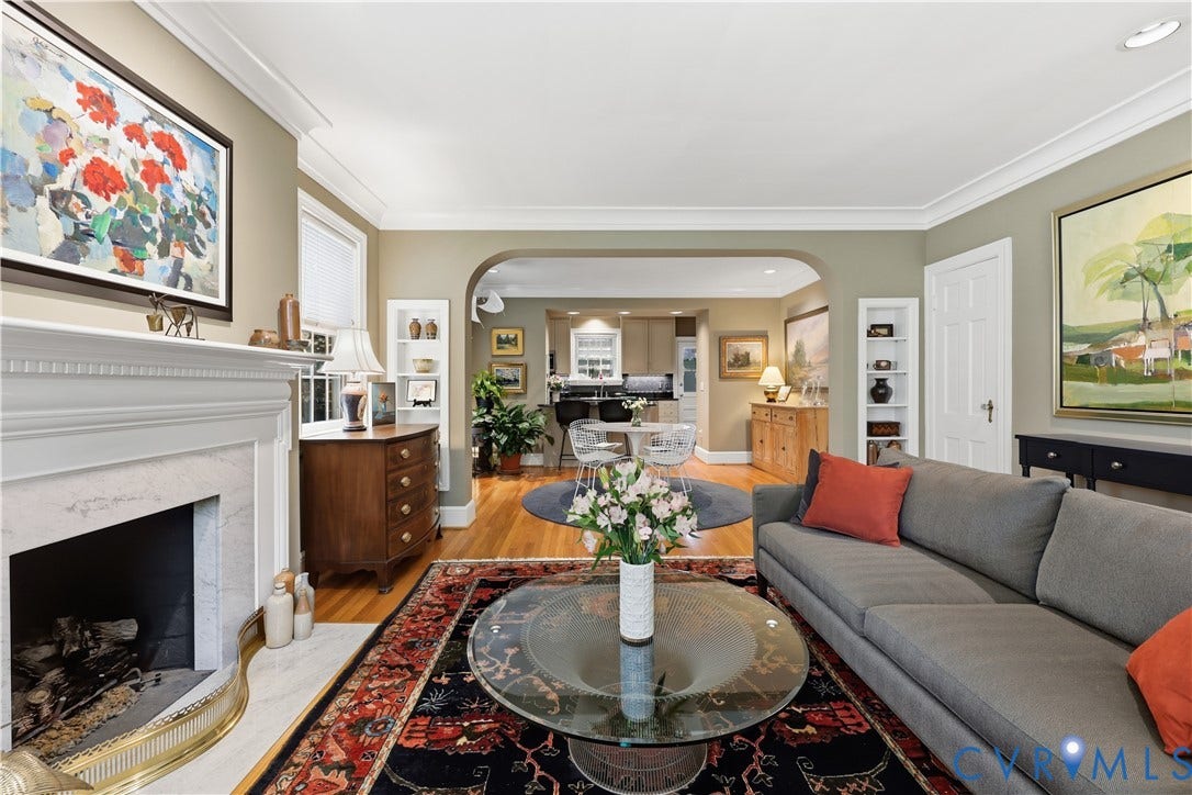 4207 W Grace Street, Sauer's Gardens, Richmond, VA 23230 Living area featuring crown molding, hardwood flooring, a white mantel fireplace with marble surround, built-in shelving, and an arched doorway