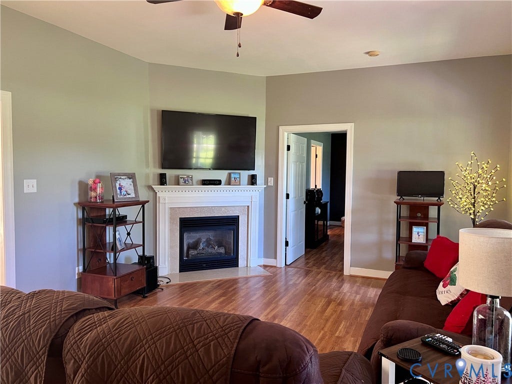 2301 Graceland Drive, Powhatan, VA 23139 Living area featuring a corner fireplace with a white mantel, wood-finish flooring, and light gray wall paint