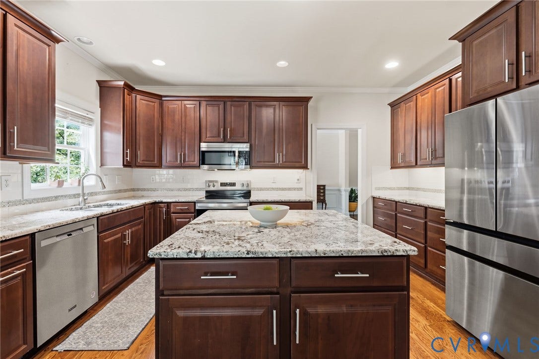 8343 Shagreen Court, The Highlands, Chesterfield, VA 23838 Kitchen featuring rich wood cabinetry, stainless steel appliances, a large center island with a stone countertop, and wood-finish flooring