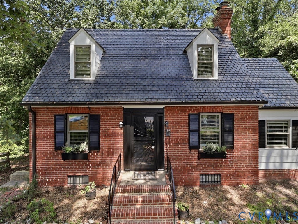 Brick exterior with a dark-pitched roof, dormer windows, and a prominent chimney