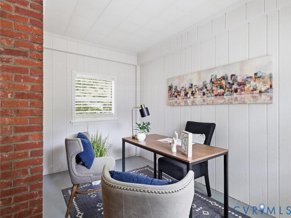 White paneled walls and ceiling, exposed brick architectural element, and a window with blinds