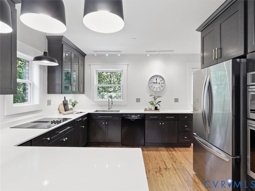 White countertops, dark wood-finish cabinetry, stainless steel appliances, built-in cooktop, and wood-finish flooring