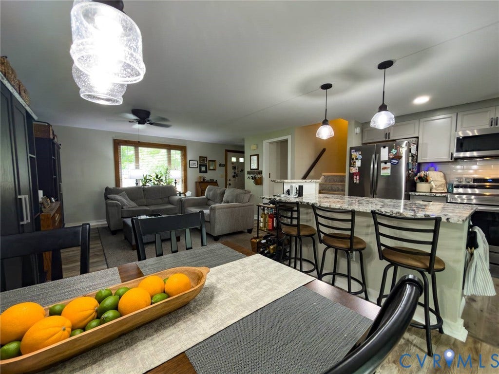 4900 Cord Court, Bridgewood, Glen Allen, VA 23060 Open-concept living space featuring a kitchen with stainless steel appliances, light-colored cabinetry, and a peninsula with seating