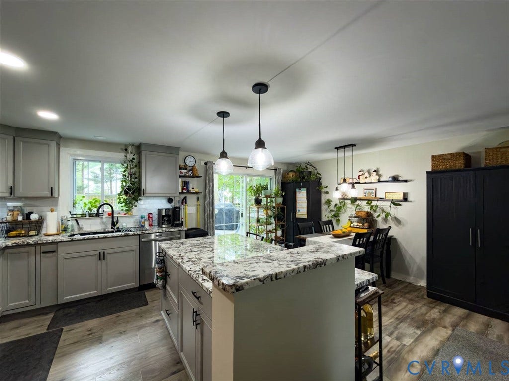4900 Cord Court, Bridgewood, Glen Allen, VA 23060 Chef's kitchen featuring white cabinetry, a large waterfall-edge quartz island with seating, stainless steel appliances, pendant lighting, and abundant natural light from multiple windows
