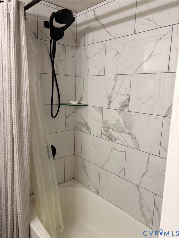 4900 Cord Court, Bridgewood, Glen Allen, VA 23060 Bathtub with subway tile surround featuring a marble-style finish, matte black shower fixtures, and a glass corner shelf