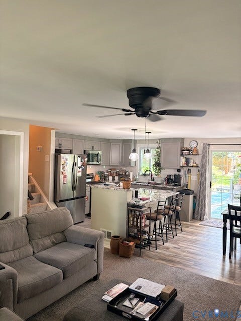 4900 Cord Court, Bridgewood, Glen Allen, VA 23060 Open concept living space featuring wood-finish flooring, a kitchen island with seating, stainless steel appliances, and light-toned cabinetry