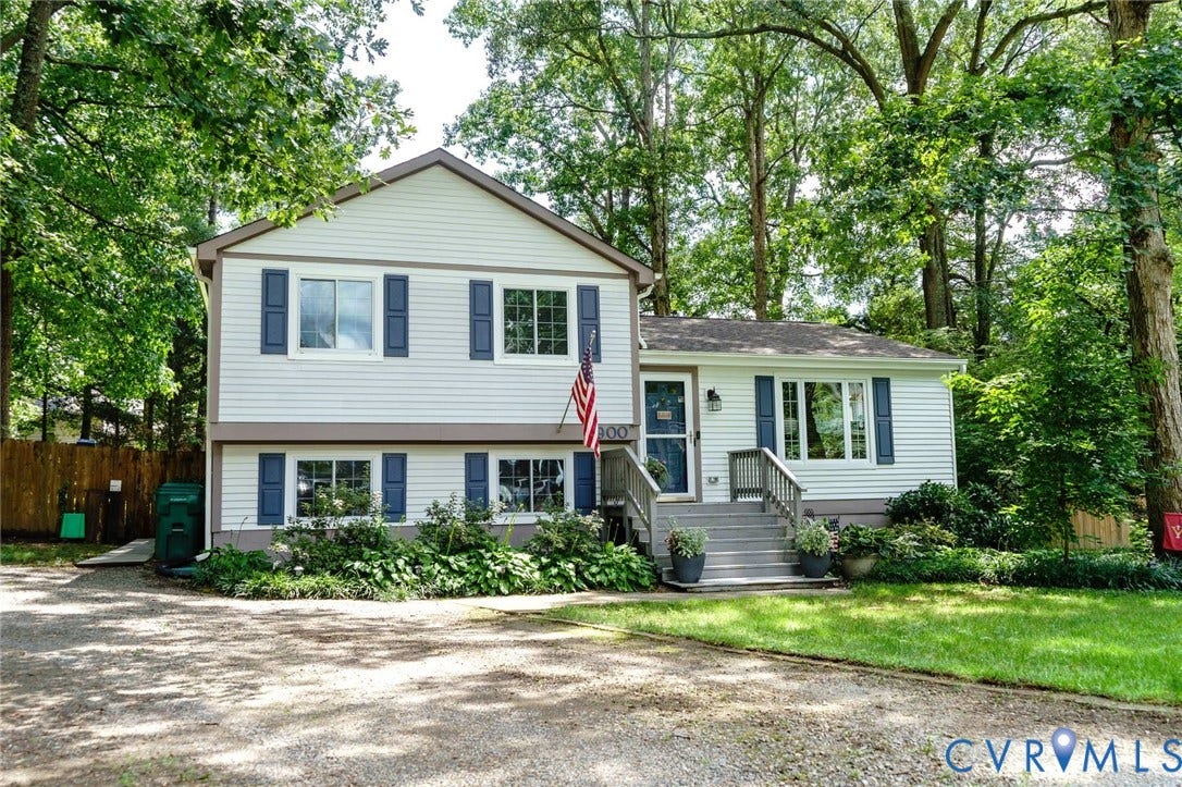 4900 Cord Court, Bridgewood, Glen Allen, VA 23060 Two-story colonial with light gray vinyl siding and dark shutters, featuring a covered front entrance with railings, multi-pane windows, and an attached single-story wing