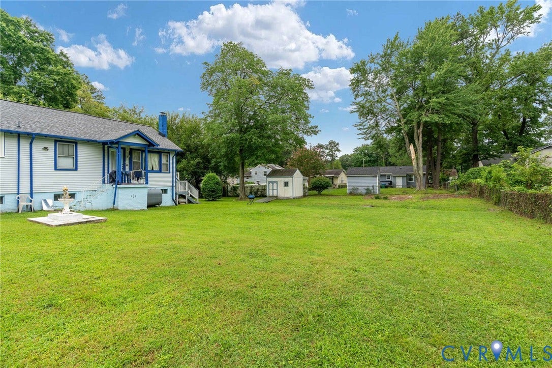 5927 Swanson Road, Richmond, VA 23225 Expansive rear yard featuring a large green lawn, mature trees, and a white exterior residence with blue trim