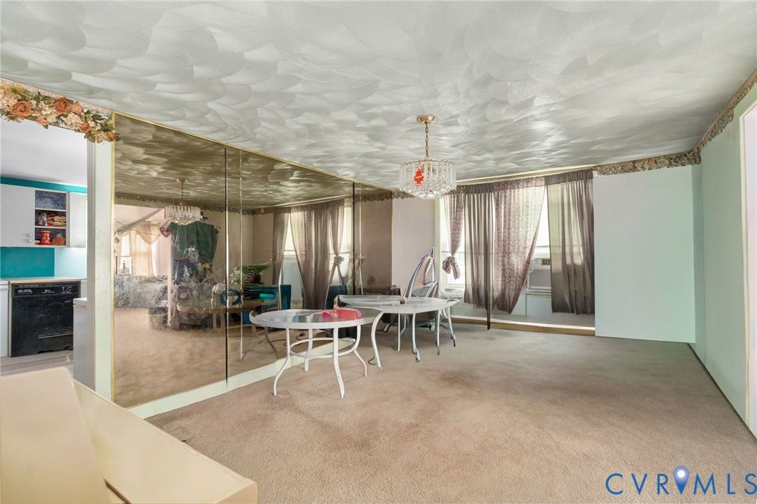 5927 Swanson Road, Richmond, VA 23225 Carpeted open area featuring a crystal chandelier, full-height mirrored wall, and a window with drapes