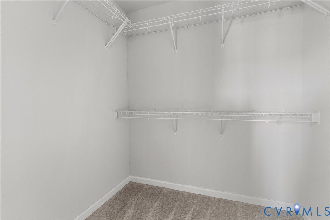Spacious walk-in closet featuring dual wire shelving systems, wood-finish flooring, and bright overhead lighting for optimal organization and visibility
