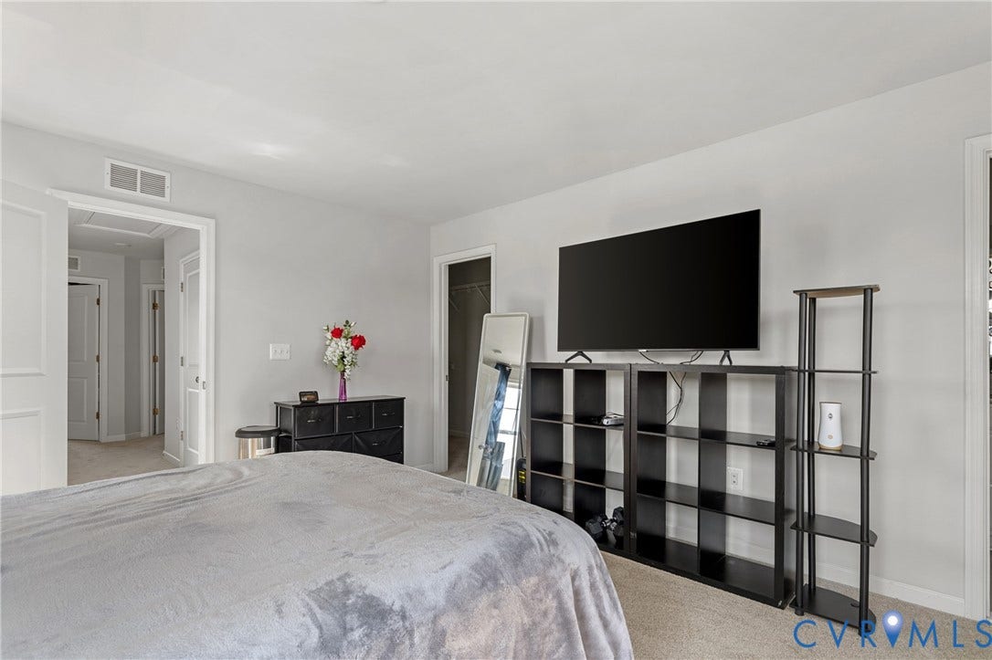 Spacious primary bedroom featuring neutral carpeting, white walls, and abundant natural light