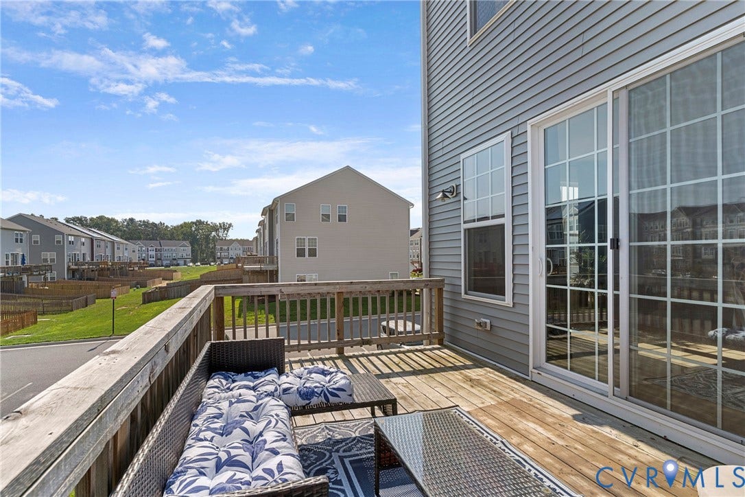Expansive composite deck featuring wood-finish decking, black metal railings, and integrated seating areas with cushioned outdoor furnishings