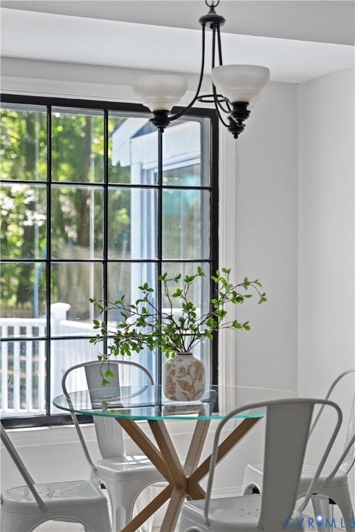 Bright dining area anchored by a black metal chandelier with frosted glass shades and a geometric wood-base table