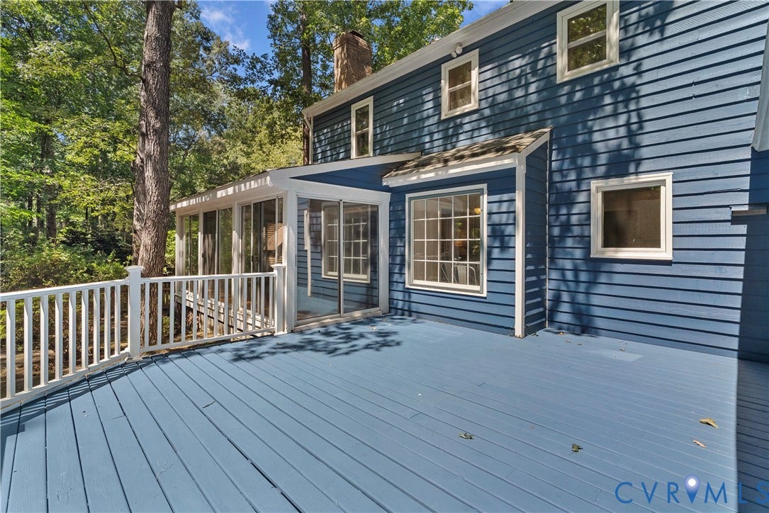 Expansive wood deck with white railing, blue exterior siding, multiple windows, and a screened-in porch