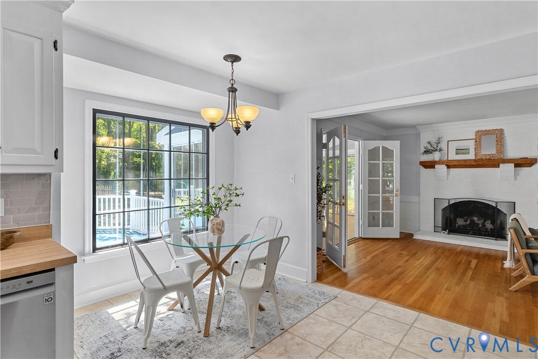 Black-framed window, tile flooring, wood-finish flooring, white cabinetry, and a fireplace with a wood mantle
