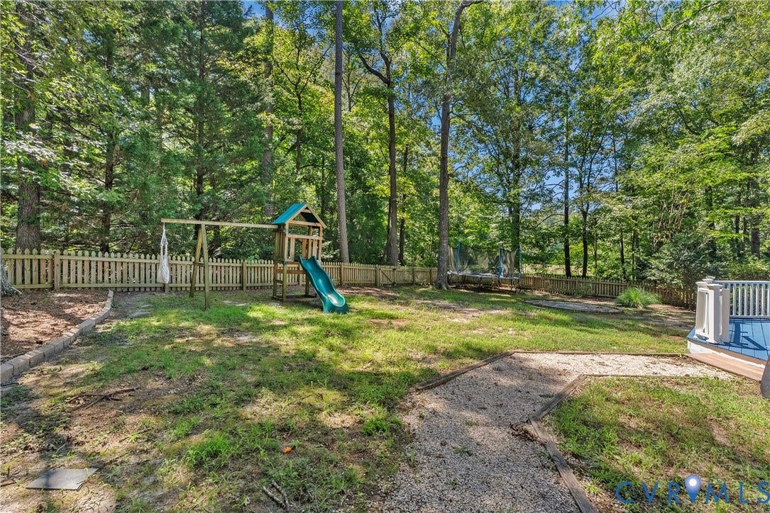 Expansive backyard featuring a wood picket fence, gravel path, and mature trees
