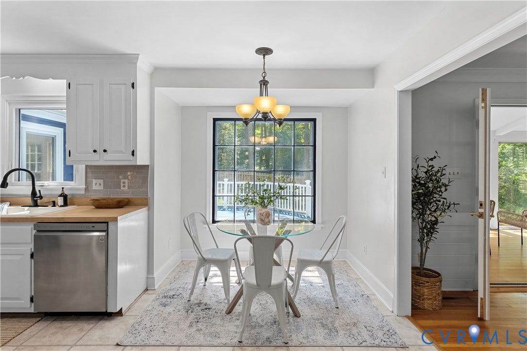 Open dining area with round pedestal table base, pendant lighting, and large multi-pane window overlooking outdoor space