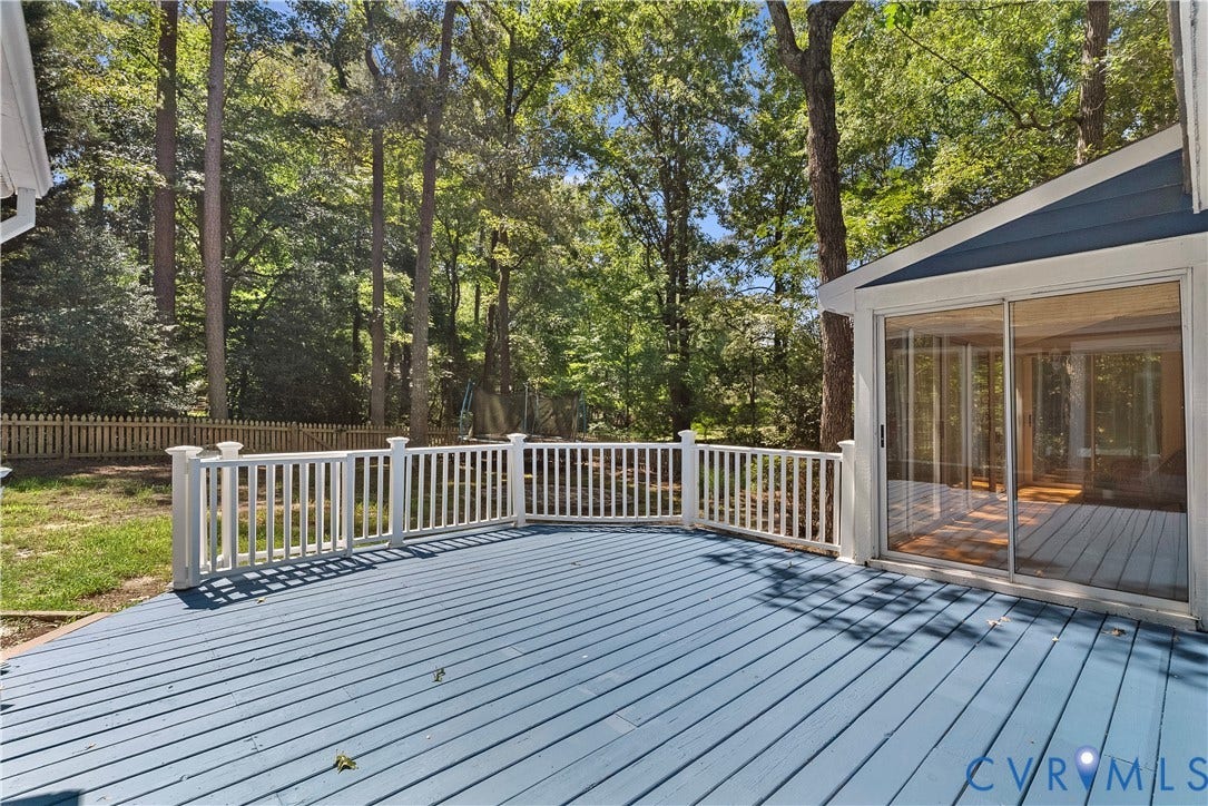 Expansive composite deck with light blue finish and white aluminum railings overlooking mature wooded landscape