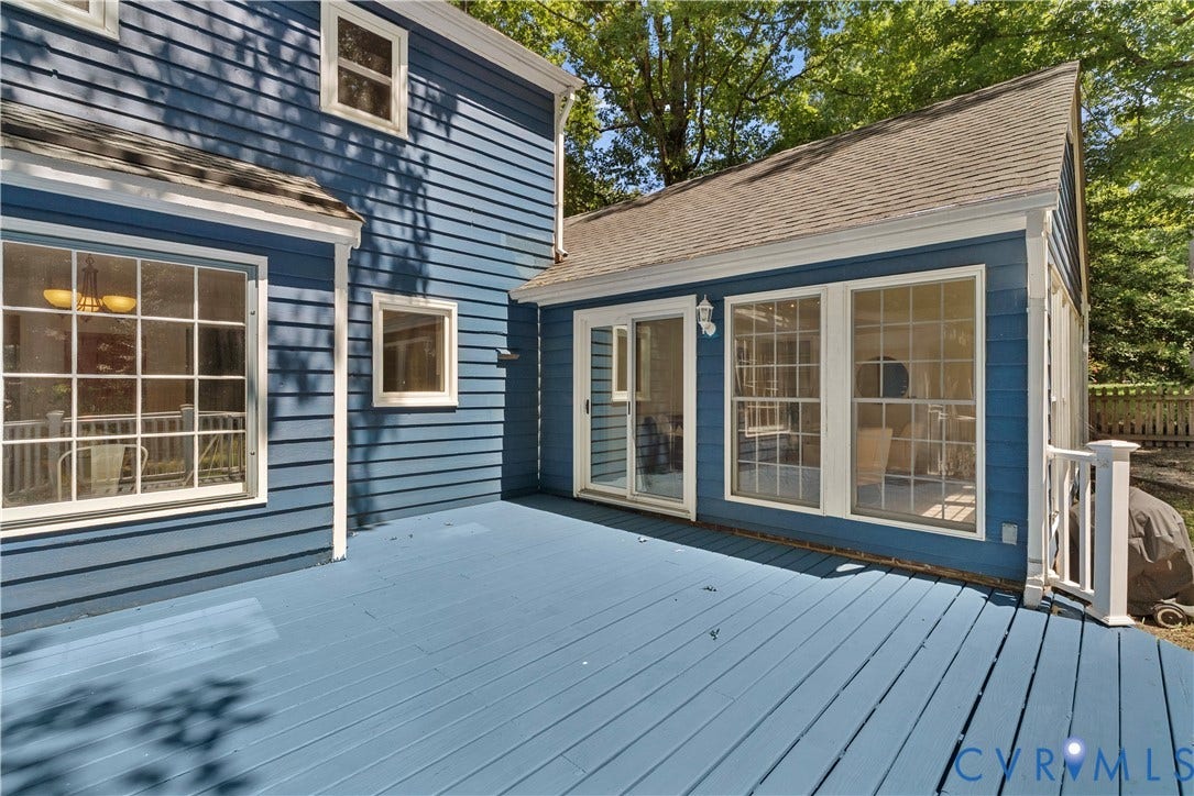 Expansive composite deck featuring light blue finish wood decking, anchored by a modern addition with large multi-pane glass doors and windows