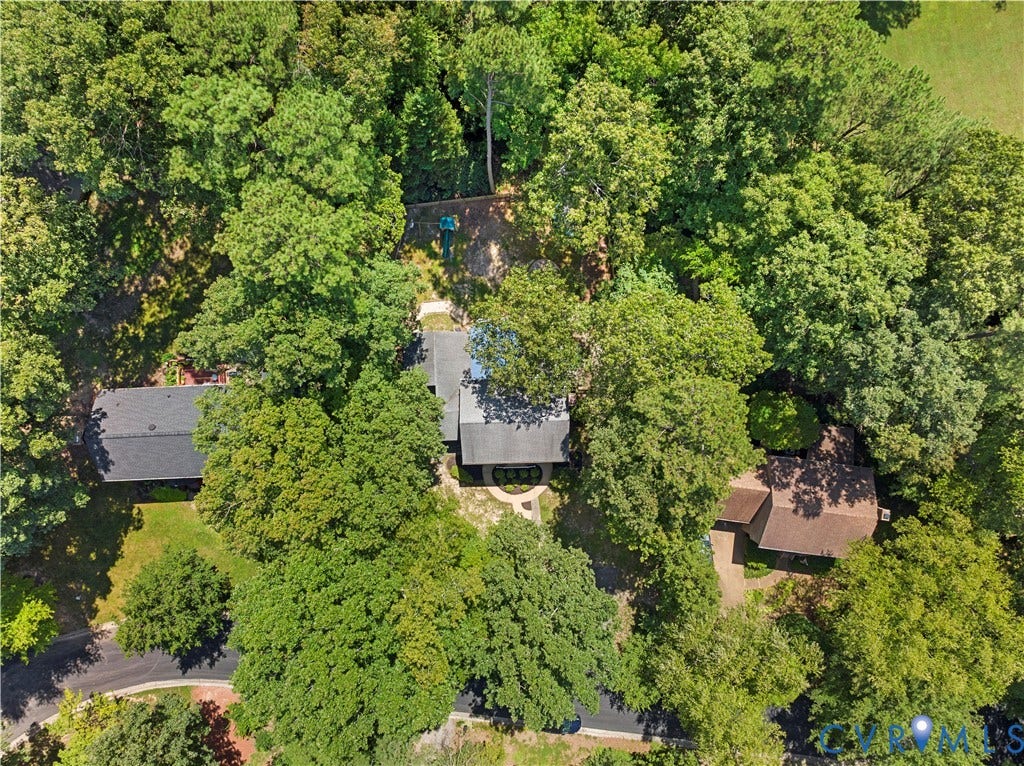 Property featuring a dark shingle roof, surrounded by mature trees