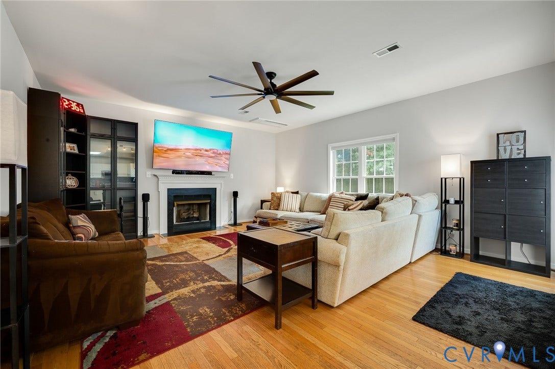 10620 Correnty Drive, Henrico, VA 23059 Spacious living area featuring light-toned walls, wood-finish flooring, a contemporary ceiling fan, recessed lighting, and a prominent fireplace with a white mantel