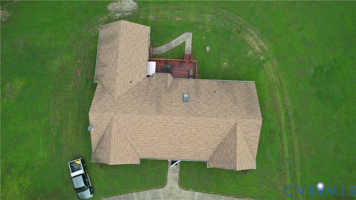 Amelia, VA 23966 Expansive green lawn surrounding a residence with a multi-pitched roofline, a visible skylight, and a rear wood deck with an attached pathway