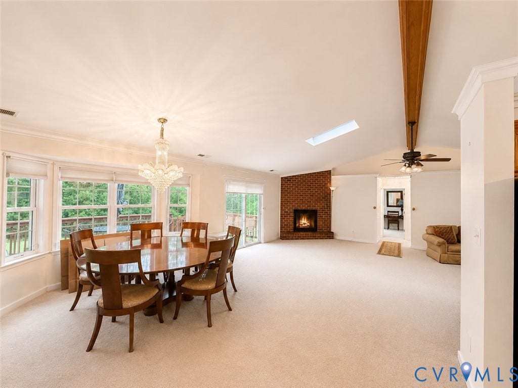 Amelia, VA 23966 Open-concept living space featuring a brick fireplace, vaulted ceiling with a skylight, and a ceiling fan