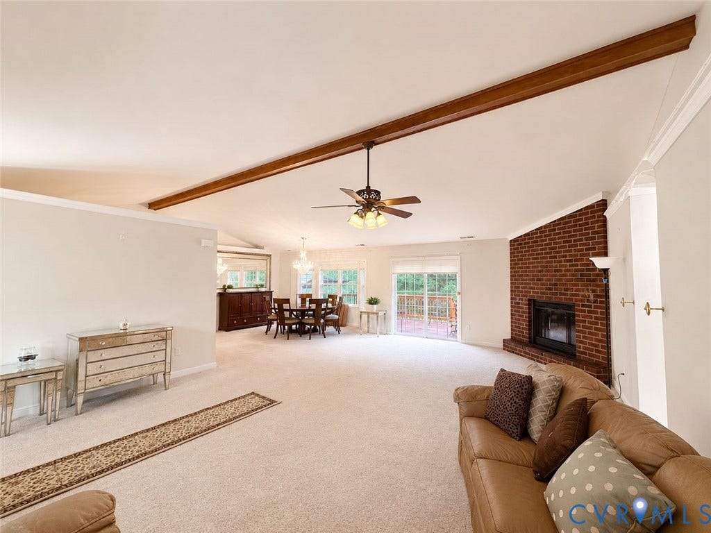 Amelia, VA 23966 Spacious living area featuring a brick fireplace, vaulted ceilings with exposed wood beams, and neutral carpeting