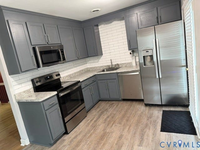 11925 Wedge Drive, Chester, VA 23831 Modern kitchen featuring gray cabinetry, stainless steel appliances, light-toned countertops, white subway tile backsplash, and wood-finish flooring