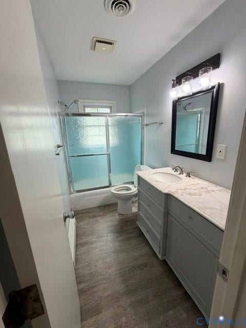11925 Wedge Drive, Chester, VA 23831 Bathroom featuring a single vanity with a white countertop and light gray cabinetry, wood-finish flooring, and a tub/shower combination with sliding frosted glass doors