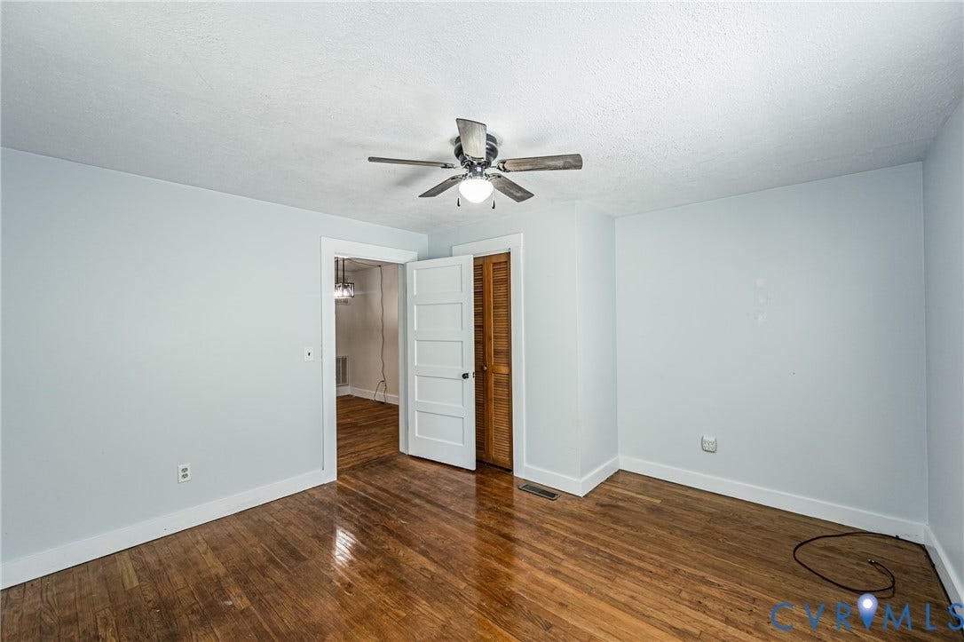 Bright room featuring wood-finish flooring, white trim, and a ceiling fan with light fixture