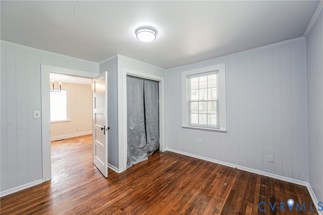 Room featuring wood-finish flooring, a double-hung window, white trim, a flush-mount ceiling light, and board-and-batten wall treatment