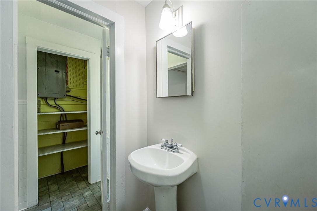 Pedestal sink with chrome fixtures and wall-mounted mirror