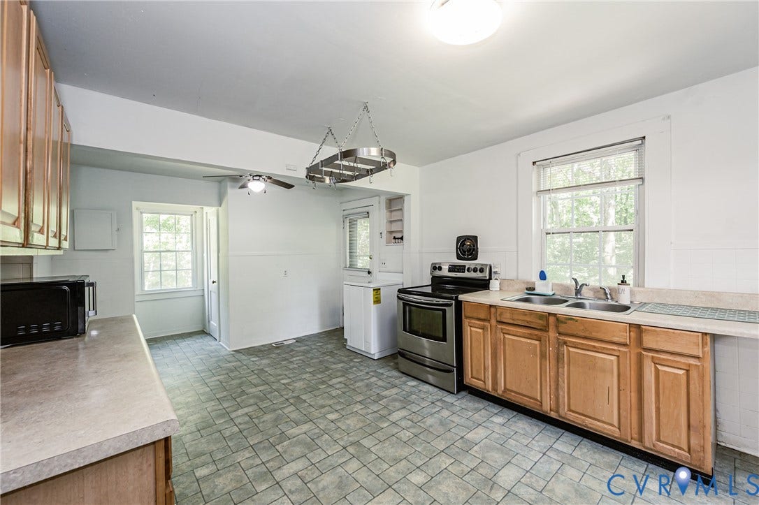 Spacious kitchen featuring neutral-toned countertops, a stainless steel range, and light wood cabinetry