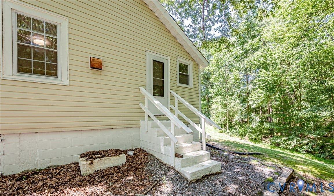 Light-colored siding exterior with white trim windows and a multi-level concrete staircase leading to an entry door