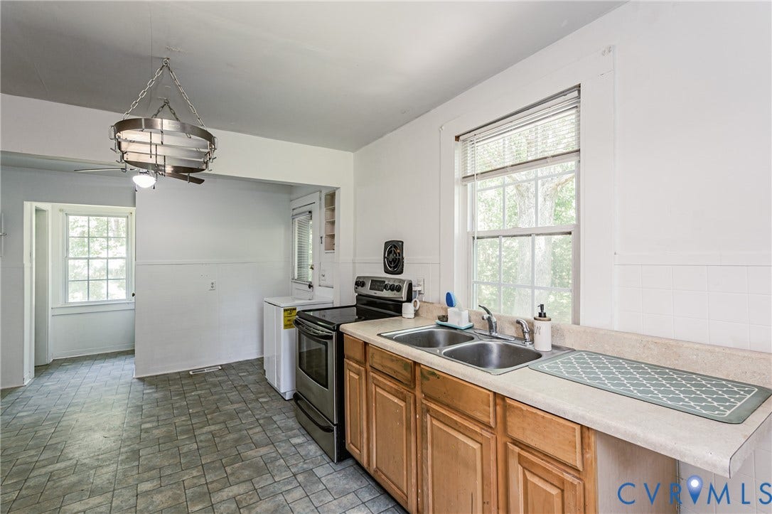 Kitchen featuring a dual basin stainless steel sink, wood-finish cabinetry, neutral countertops, and tile flooring