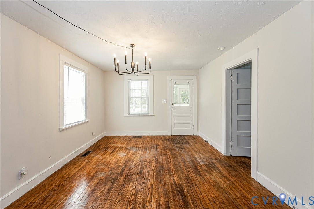 Hardwood flooring extends throughout this room, featuring two windows with white trim