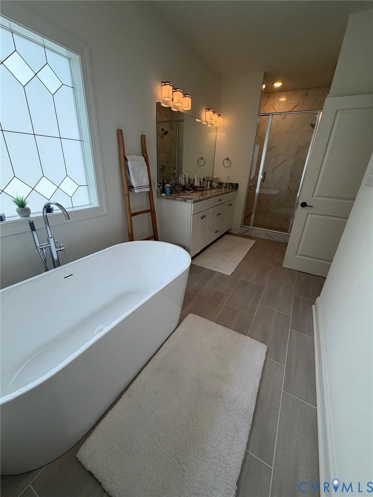 4516 Bacova Club Court, Glen Allen, VA 23059 Freestanding soaking tub with floor-mounted faucet, dual vanity with undermount sinks, frameless glass shower enclosure, and rectangular tile flooring