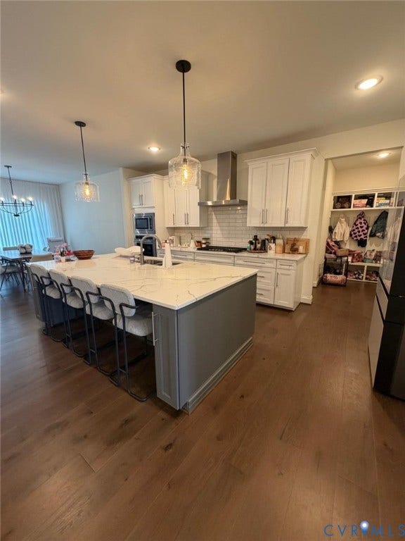 4516 Bacova Club Court, Glen Allen, VA 23059 Gourmet kitchen with wood-finish flooring, a large island featuring a light-toned countertop, white cabinetry, and stainless steel appliances