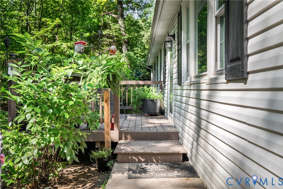 3940 Three Bridge Road, Powhatan, VA 23139 Wood-finish decking with railings, steps, and concrete path leading to siding exterior with multiple windows and dark-toned shutters