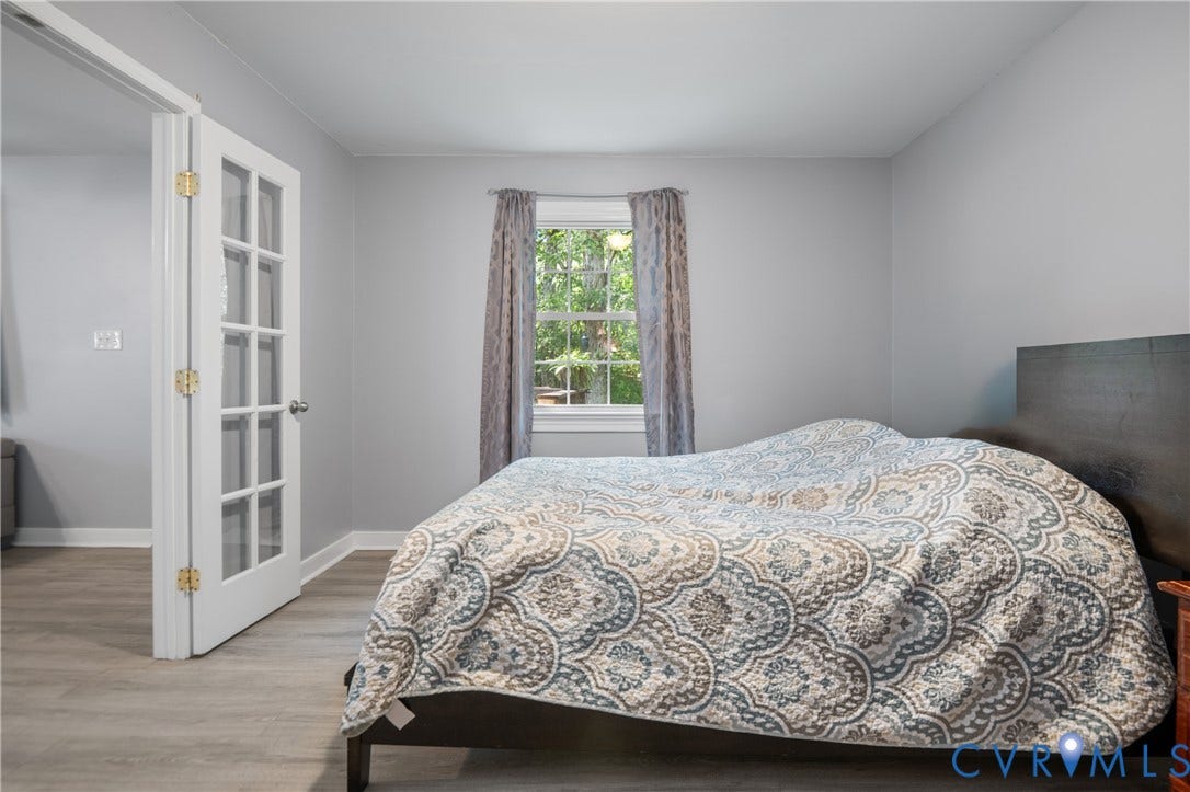 3940 Three Bridge Road, Powhatan, VA 23139 Light gray wall paint, wood-finish flooring, white window trim, and a white French door with brass-finish hardware