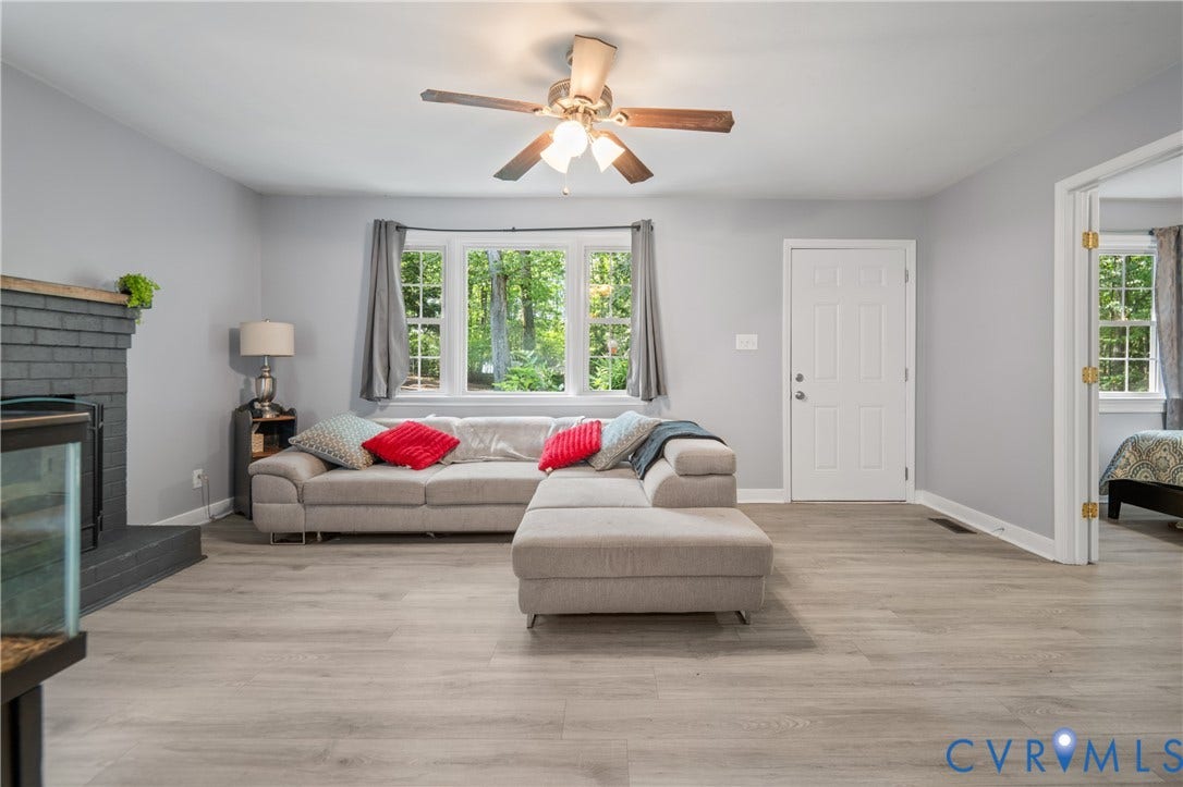 3940 Three Bridge Road, Powhatan, VA 23139 Wood-finish flooring throughout, ceiling fan, white paneled door, and a painted brick fireplace with a wood mantel
